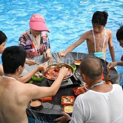 波のプールや水に浸かって火鍋を楽しむ重慶の人々